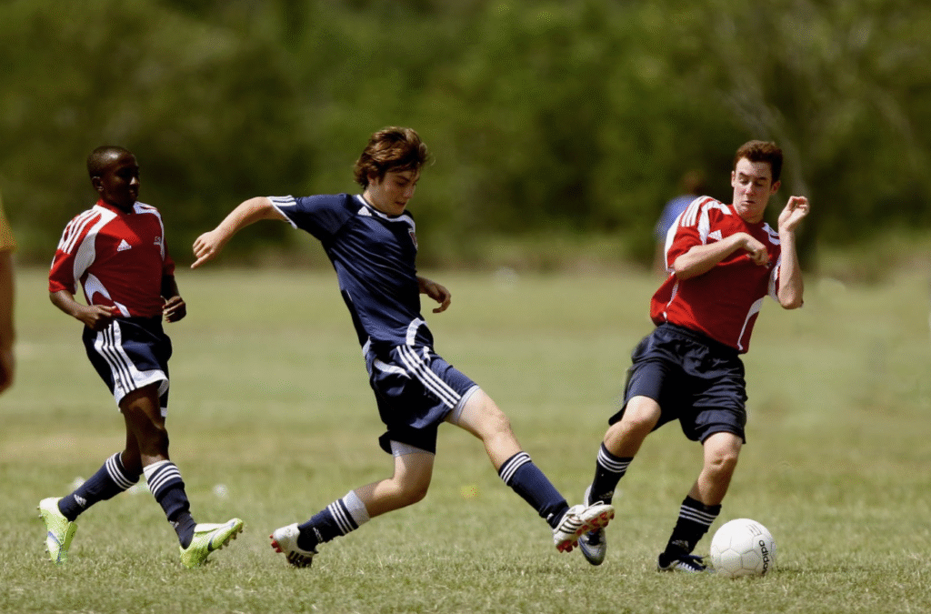 Football players training on field with coach demonstrating proper techniques and skills development
