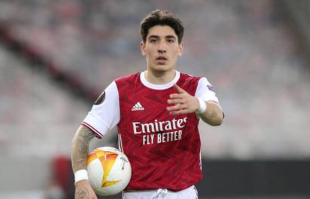Professional footballer in red Adidas jersey running with ball during match showing athletic performance and conditioning