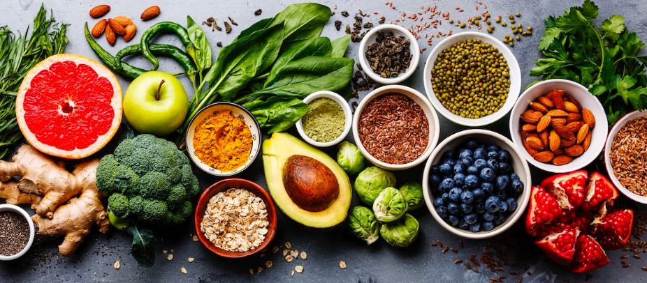 Colorful array of nutrient-dense foods including fruits, vegetables, nuts, seeds, and healthy fats for football nutrition