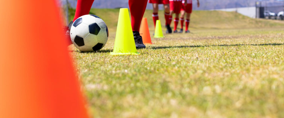 Football players training on grass field with soccer ball and training equipment for athletic development
